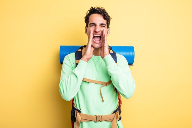 Jeune bel homme se sentant heureux, donnant un grand cri avec les mains à côté de la bouche