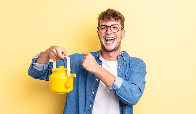 Jeune bel homme se sentant heureux et faisant face à un défi ou célébrant le concept de théière