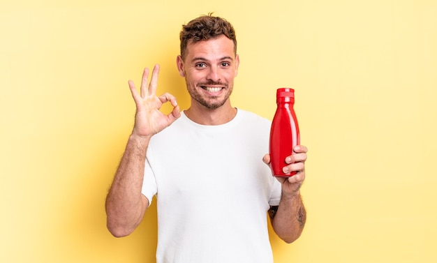 Jeune bel homme se sentant heureux montrant son approbation avec le concept de ketchup de geste correct