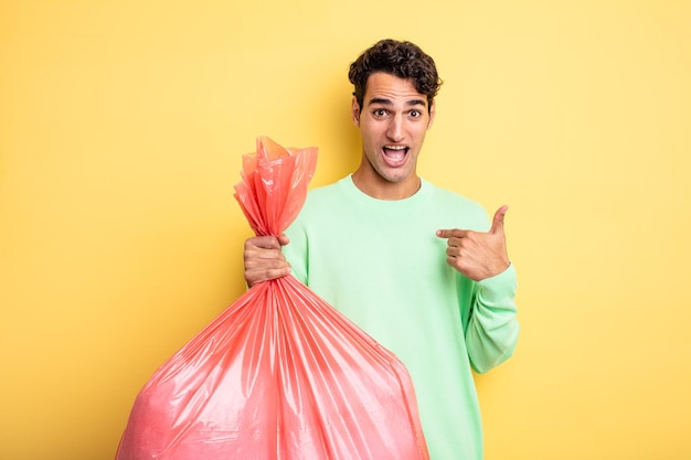 Jeune bel homme se sentant heureux et pointant vers lui-même avec un excité. concept de sac poubelle