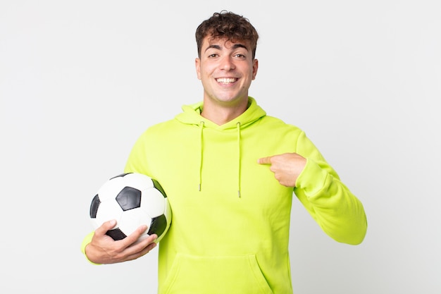 Jeune Bel Homme Se Sentant Heureux Et Pointant Vers Soi Avec Un Excité Et Tenant Un Ballon De Football