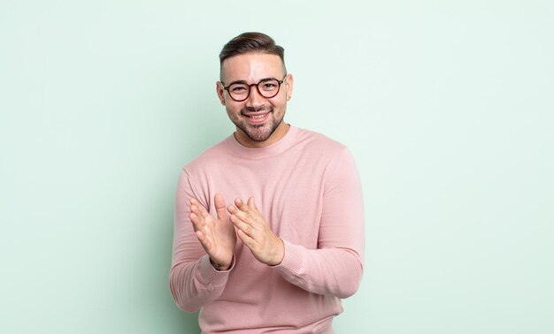 Jeune bel homme se sentant heureux et réussi en souriant et en frappant des mains en disant félicitations avec des applaudissements