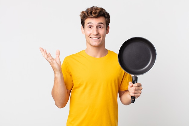 Jeune bel homme se sentant heureux, surpris de réaliser une solution ou une idée et tenant une casserole