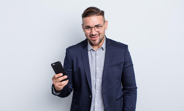 Jeune bel homme se sentant perplexe et confus concept d'entreprise et de smartphone