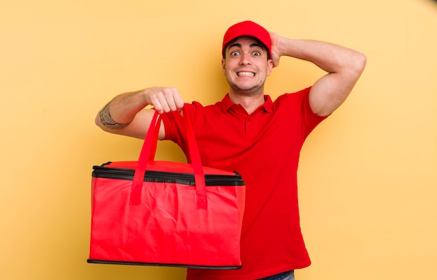 Jeune bel homme se sentant stressé anxieux ou effrayé avec les mains sur la tête concept de courrier de pizza