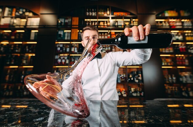 Jeune bel homme sommelier dégustation de vin rouge en cave