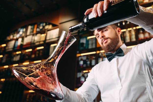 Jeune bel homme sommelier dégustation de vin rouge en cave