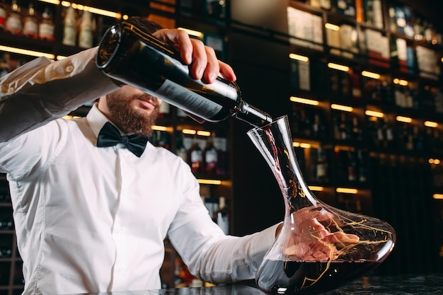 Photo jeune bel homme sommelier dégustation de vin rouge en cave.