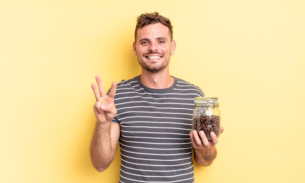 jeune bel homme souriant et à l'air sympathique, montrant le concept de grains de café numéro trois