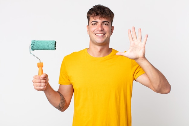 jeune bel homme souriant et à l'air sympathique, montrant le numéro cinq. concept de maison de peinture