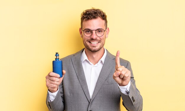 jeune bel homme souriant et à l'air sympathique, montrant le numéro un. concept de vaporisateur