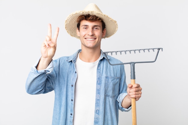 Jeune bel homme souriant et à l'air sympathique, montrant le numéro deux. concept d'agriculteur