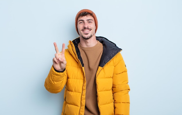 Jeune bel homme souriant et à l'air sympathique, montrant le numéro deux. notion d'hiver