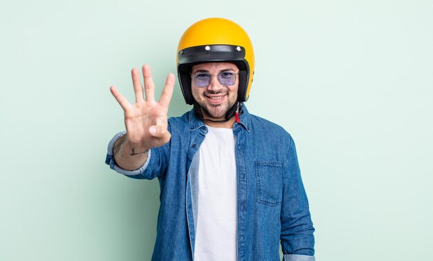 Jeune bel homme souriant et à l'air sympathique, montrant le numéro quatre. concept de casque de moto