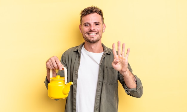 jeune bel homme souriant et à l'air sympathique, montrant le numéro quatre. notion de théière