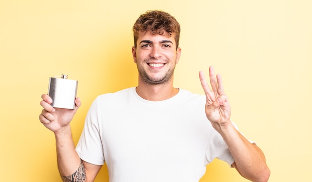 jeune bel homme souriant et à l'air sympathique, montrant le numéro trois. concept de flacon d'alcool