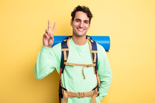 Jeune bel homme souriant et ayant l'air heureux, gesticulant la victoire ou la paix