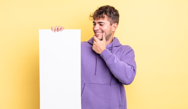 Jeune bel homme souriant avec une expression heureuse et confiante avec la main sur le menton. concept d'espace de copie