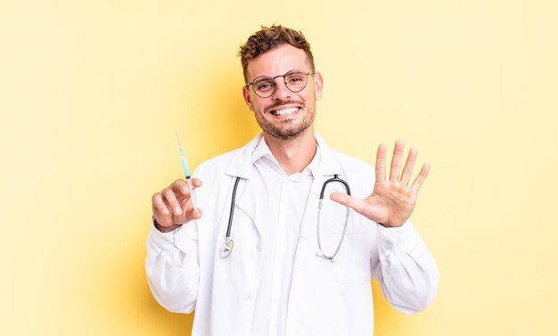 Jeune bel homme souriant et semblant amical, montrant le numéro cinq. concept de seringue de médecin