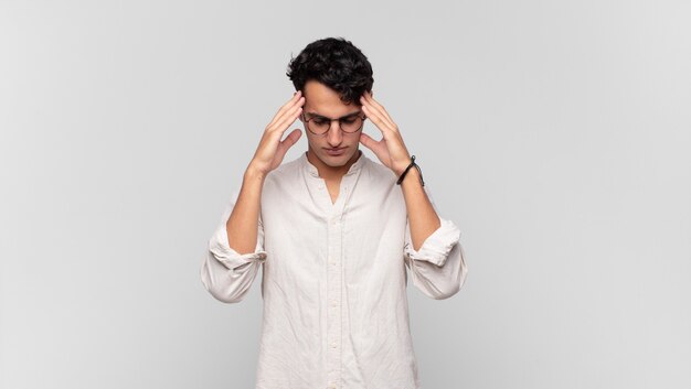 Jeune bel homme à la stress et frustré, travaillant sous pression avec un mal de tête et troublé par des problèmes