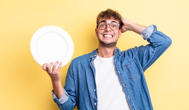 Jeune bel homme stressé, anxieux ou effrayé, les mains sur la tête. concept de plat vide