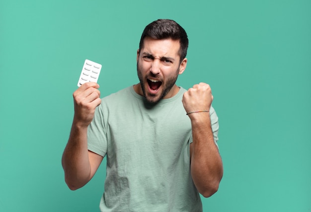 Jeune bel homme avec une tablette de pilules. concept de maladie ou de douleur