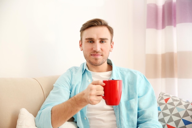 Jeune bel homme avec une tasse de café à la maison