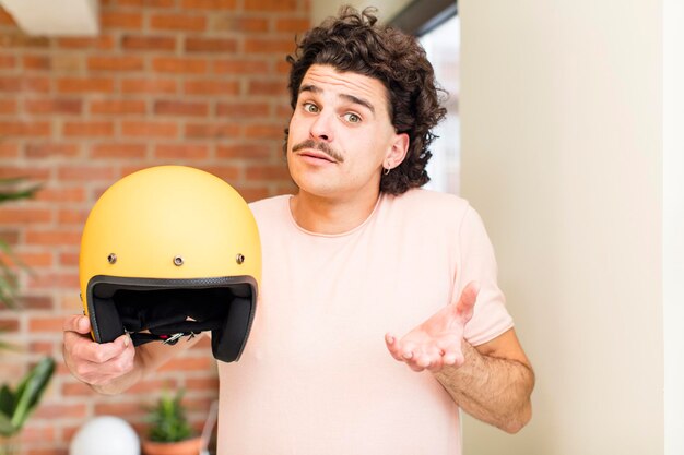 Jeune bel homme tenant un casque de moto à l'intérieur de la maison