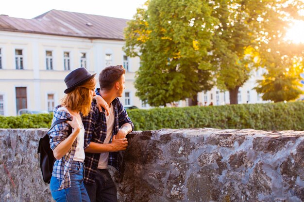 Jeune bel homme tenant une jolie femme pointant vers des sites intéressants, tous deux debout près du château médiéval. Concept de voyage en famille