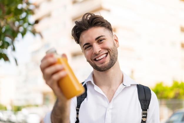 Jeune bel homme tenant un jus d'orange à l'extérieur