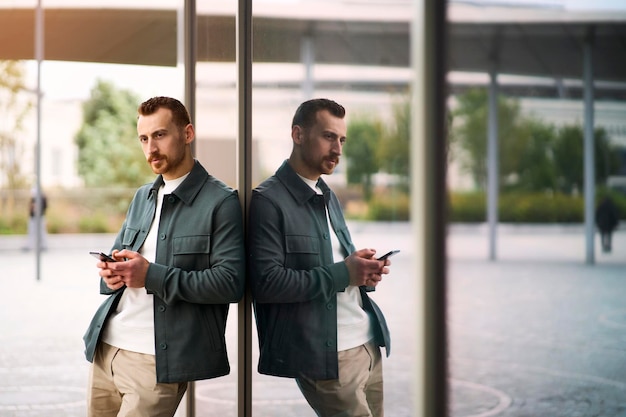 Jeune bel homme tenant un smartphone à l'aide d'une application mobile faisant des achats en ligne