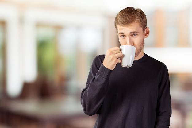 Jeune bel homme tenant une tasse de thé / café