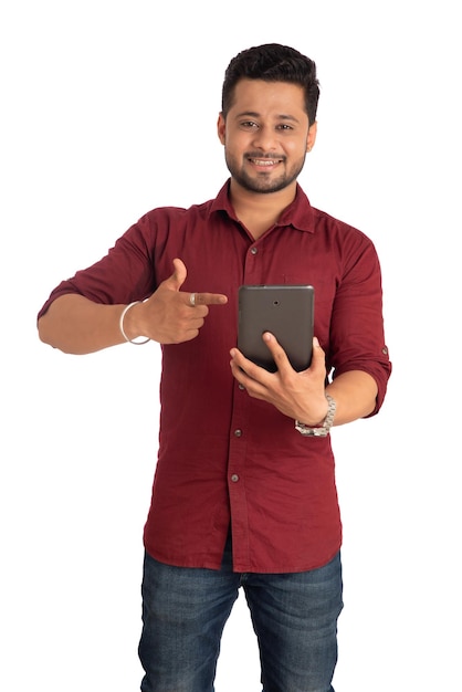 Jeune bel homme tenant et utilisant un smartphone ou un téléphone portable ou une tablette sur fond blanc