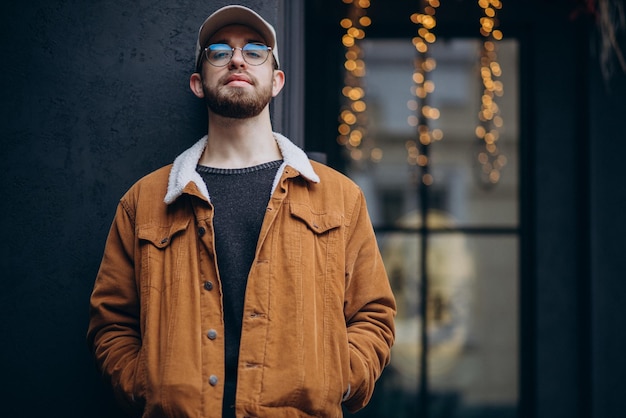 Jeune bel homme en veste posant dans la rue en hiver