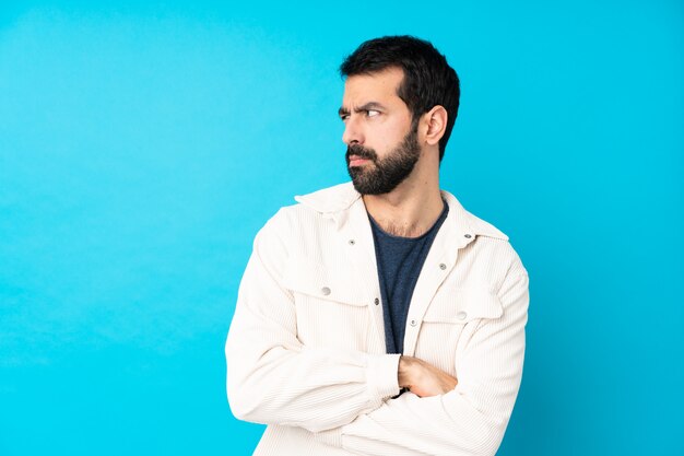 Jeune bel homme avec une veste en velours côtelé blanc sur portrait de mur bleu isolé