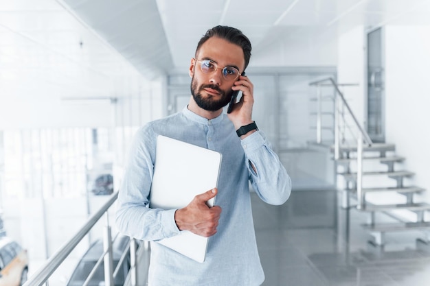 Jeune bel homme en vêtements formels à l'intérieur du bureau pendant la journée