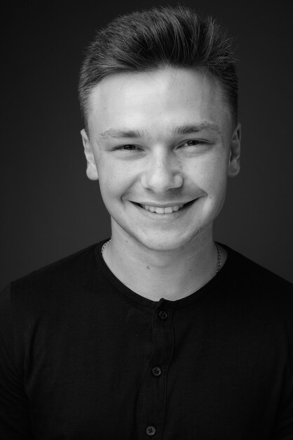 Photo jeune bel homme vêtu d'une chemise noire contre le mur gris. noir et blanc