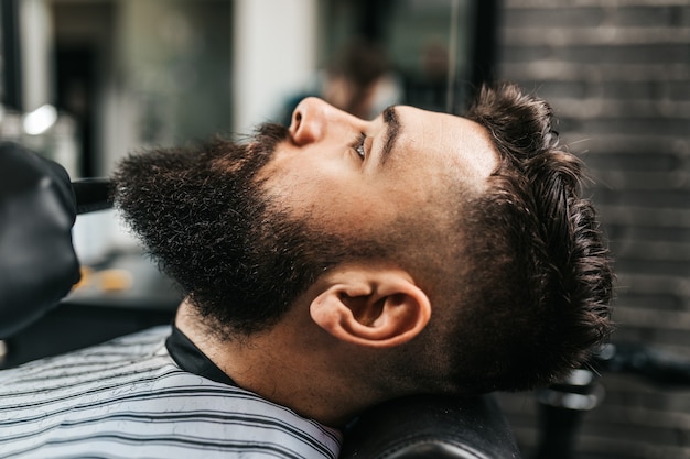 Jeune bel homme visitant un salon de coiffure. Style et coupe de barbe à la mode et élégants.