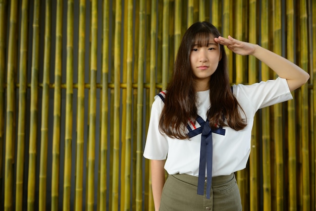 Photo jeune belle adolescente asiatique contre une clôture en bambou