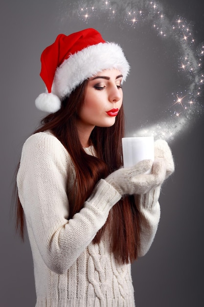 Jeune et belle adolescente en bonnet de noel avec une tasse de café chaud