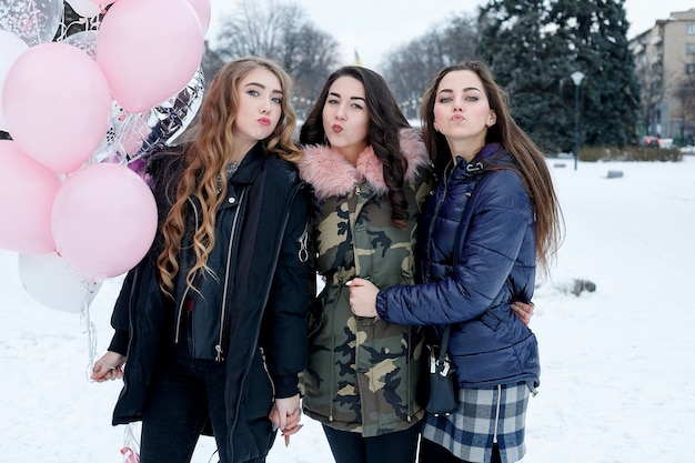 Jeune belle amie joyeuse dans des vestes colorées s'amusant et marchant dans la rue de la ville