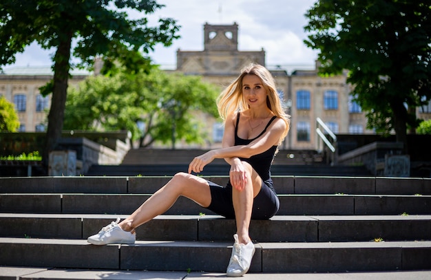 Jeune belle blonde femme sportive dans un débardeur noir et en noir serré