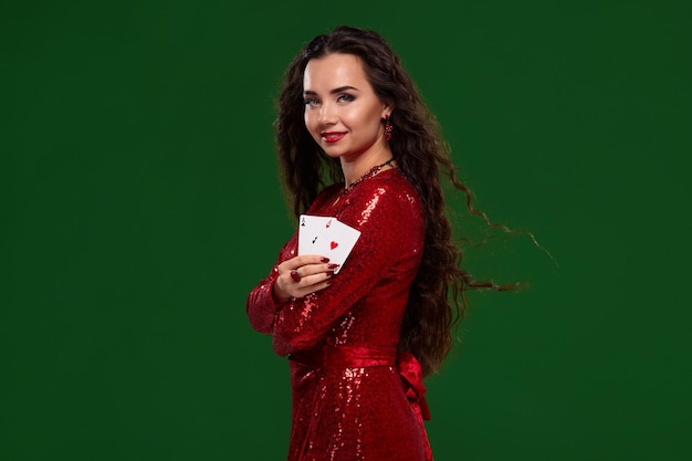 Jeune belle brune chanceuse en robe de soirée rouge montre à ses cartes une paire d'as sur fond vert...