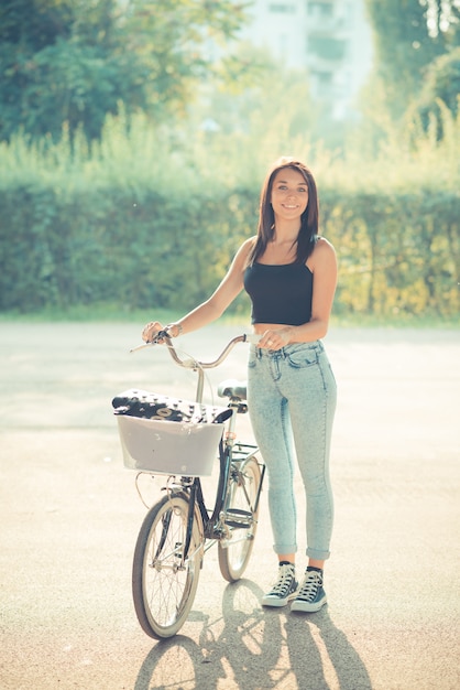 Photo jeune belle brune cheveux raides femme à l'aide de vélo