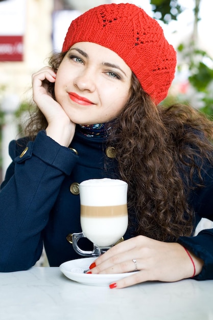 Jeune belle brune dans un béret en tricot rouge et un manteau