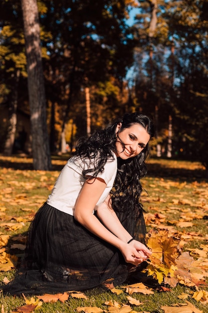 Jeune belle brune heureuse se promène dans le parc en automne