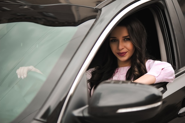 Jeune belle brune à l'intérieur de la voiture noire.