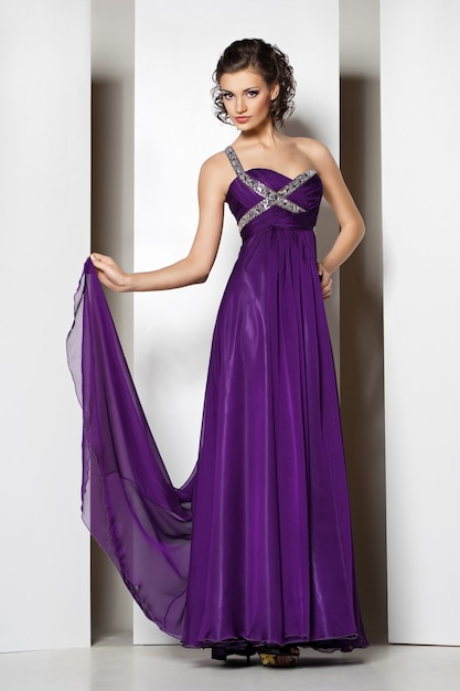 Jeune belle brune en robe violette sur blanc