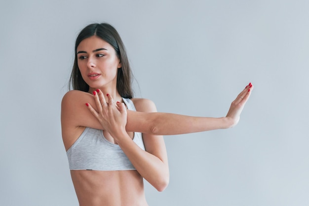 Jeune belle brune en sous-vêtements est à l'intérieur dans le studio sur fond blanc.