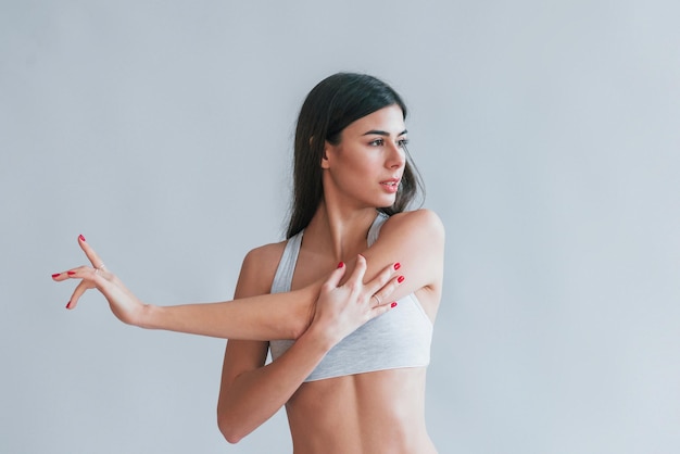 Jeune belle brune en sous-vêtements est à l'intérieur dans le studio sur fond blanc.